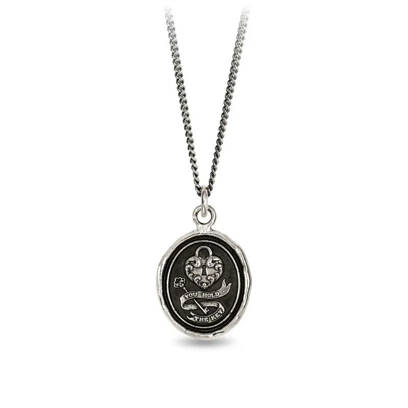 Sterling Silver talisman depicting a heart with a lock on it, above a key surrounded by a ribbon with the words, "you hold the key" written on it