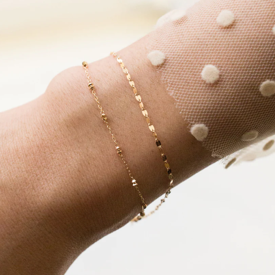 This 18-karat gold bracelet features two distinctive strands—one adorned with faceted gold beads and the other with small diamond-cut discs | on model