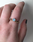 Two rings worn by a model with dark nailpolish. One is a gold-filled beaded band. The other is a hammered gold-filled band set with a pale blue aquamarine in a bezel. 