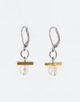 Pictured: drop earrings on white background, composed of a surgical steel leverback closure connected by a jump loop to a horizontal gold-coloured bar set atop a pale agate stone. The agates are spherical and polished, and appeared to be drilled through, as the silver-coloured disc at the end of the bead pin is slightly visible at the bottom. Faint greyish inclusions are visible in both, though more visible in the left.