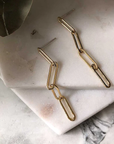 Gold-filled chain earrings displayed on marble. The earrings are composed of four narrow oval links, the first of which is attached to a stud post. 