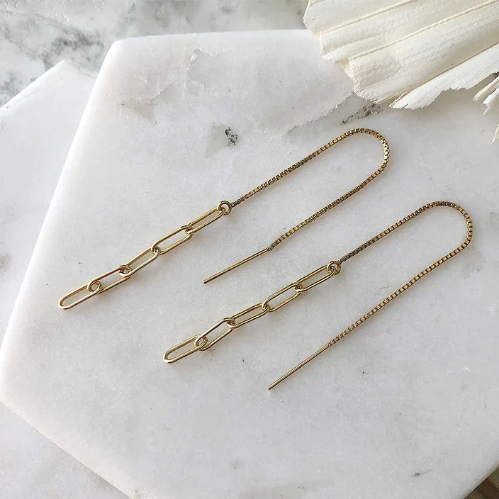 Gold-filled chain threader earrings displayed on marble. The earrings are compose of five narrow links, the first of which is attached to a long piece of fine box chain with an earring post at one end.  | Magpie Jewellery