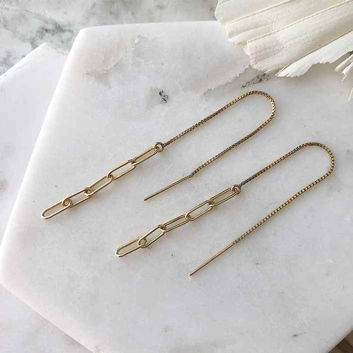 Gold-filled chain threader earrings displayed on marble. The earrings are compose of five narrow links, the first of which is attached to a long piece of fine box chain with an earring post at one end. 