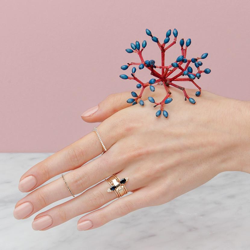 14-karat gold ring showcasing a prong-set oval-shaped Sapphire with three light-catching diamonds. Set at the top of a slim gold band for an adornment | on model