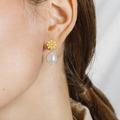  A daisy casted in 14-karat solid gold paired with a large lustrous oval pearl drop | on model