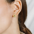 A pair of cheerful daisies casted in 14-karat solid gold with a precious Blue Sapphire in the center