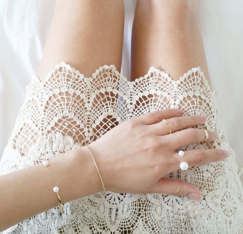 Two round freshwater cultured pearls atop a handcrafted 14-karate solid gold band.  | on model