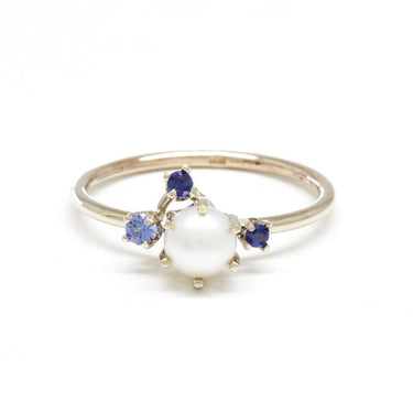 This cluster ring showcases a white pearl at its center, adorned by three radiant Blue Sapphires that add sparkle and color. | on model