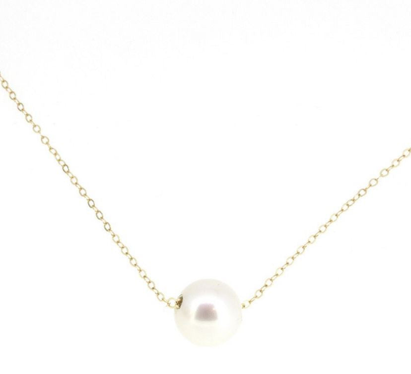 A single luscious round white pearl on a delicate 14-karat shimmering gold chain