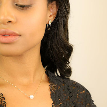A single luscious round white pearl on a delicate 14-karat shimmering gold chain | on model