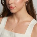 An oval shaped pearl pendant on a dainty 14-karat gold chain with little gold bead details.  | on model