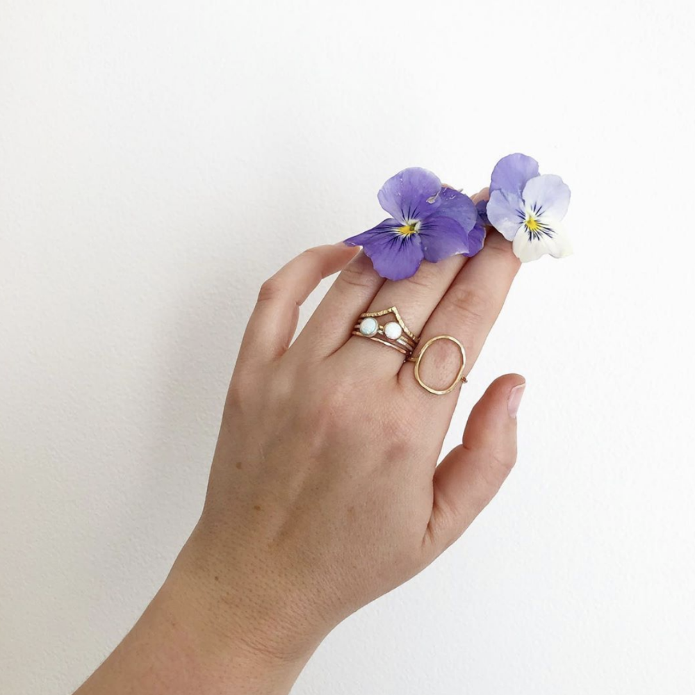 A model holding flowers and wearing a selection of gold rings, including the chevron band. 