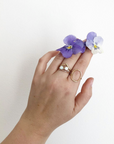 A model holding flowers and wearing a selection of gold rings, including the chevron band. 