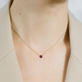 A vibrant heart shaped gemstone pendant on a dainty 14-karat gold chain.  | on model