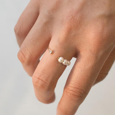 A trio of sweet baby pearls on one side and a dazzling diamond on the opposite in an open ring style.  | on model