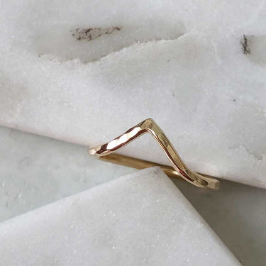 A hammered gold-filled ring with a pointed chevron. Displayed on marble.  | Magpie Jewellery