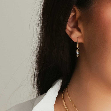 Dark pearl drop earrings on gold-filled leverback hooks embellished with three polished gold-filled beads each. Worn by model. Length hits corner of jaw.  | Magpie Jewellery